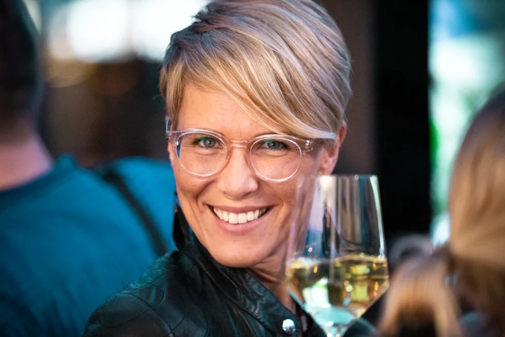Gästin mit Brille und Sektglas lächelt in die Kamera