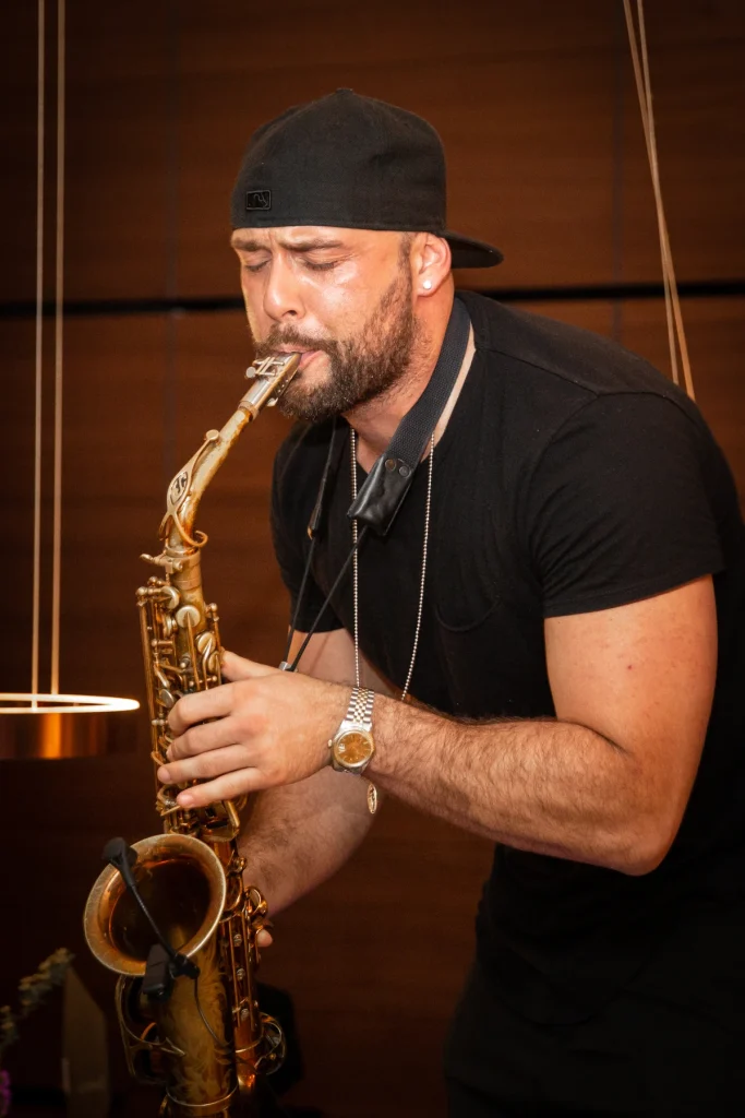 Saxophonist mit Cap spielt im Store, im Hintergrund hängen Pendelleuchten
