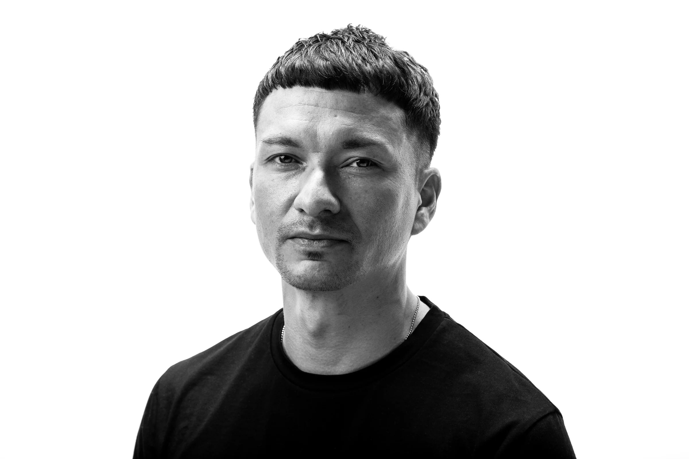 Schwarzweiß-Porträt von Genji Yoshida mit Blick in die Kamera vor weißem Hintergrund