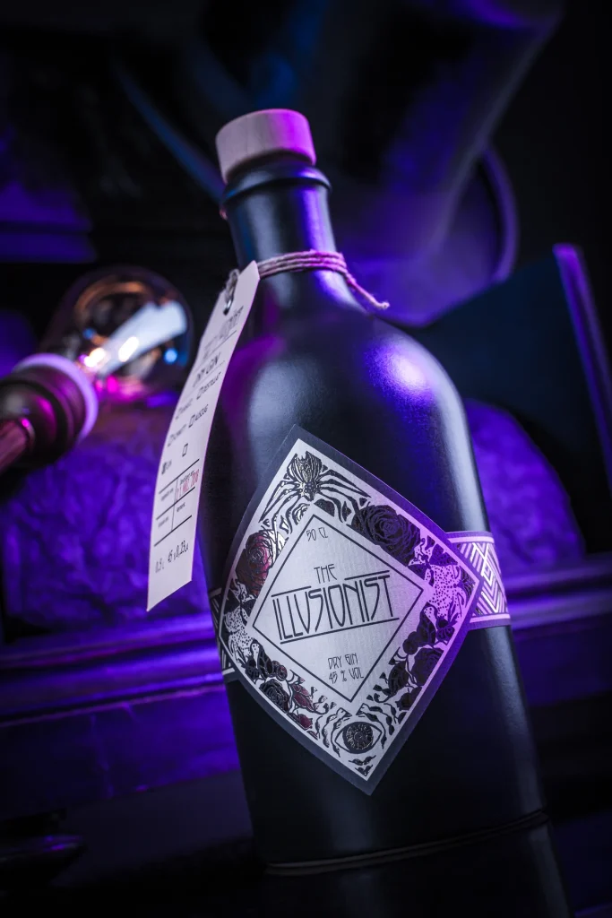 Nahaufnahme der schwarzen Flasche mit Anhänger und Rautenetikett in violettem Licht