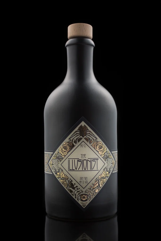 Schwarze Keramikflasche „The Illusionist Dry Gin“ mit Rautenetikett vor schwarzem Hintergrund