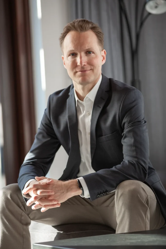 Johannes Rauch im Sakko sitzend, die Hände gefaltet, Blick in die Kamera