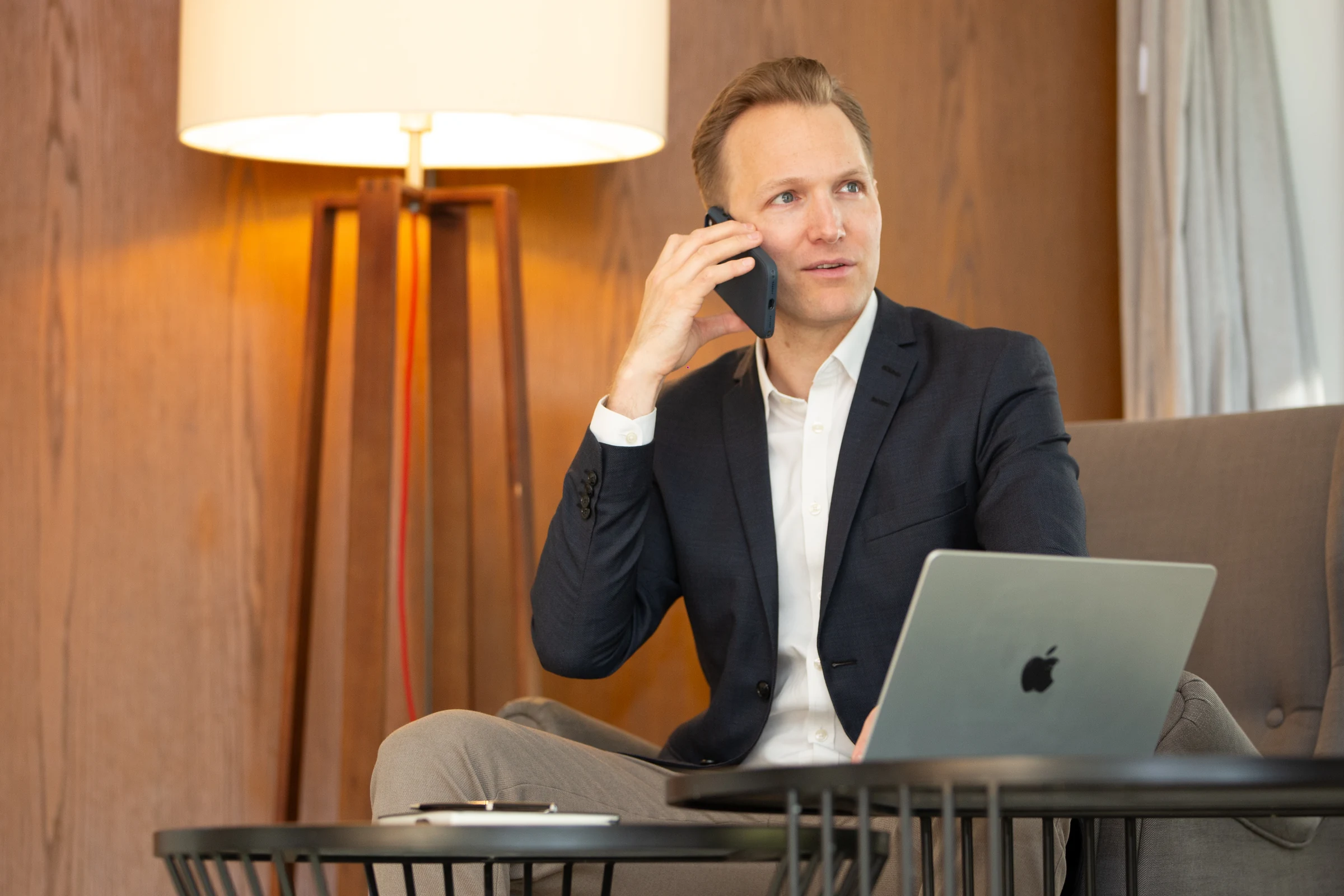 Johannes Rauch im Sakko telefoniert in einer Sitzecke, vor ihm ein Laptop